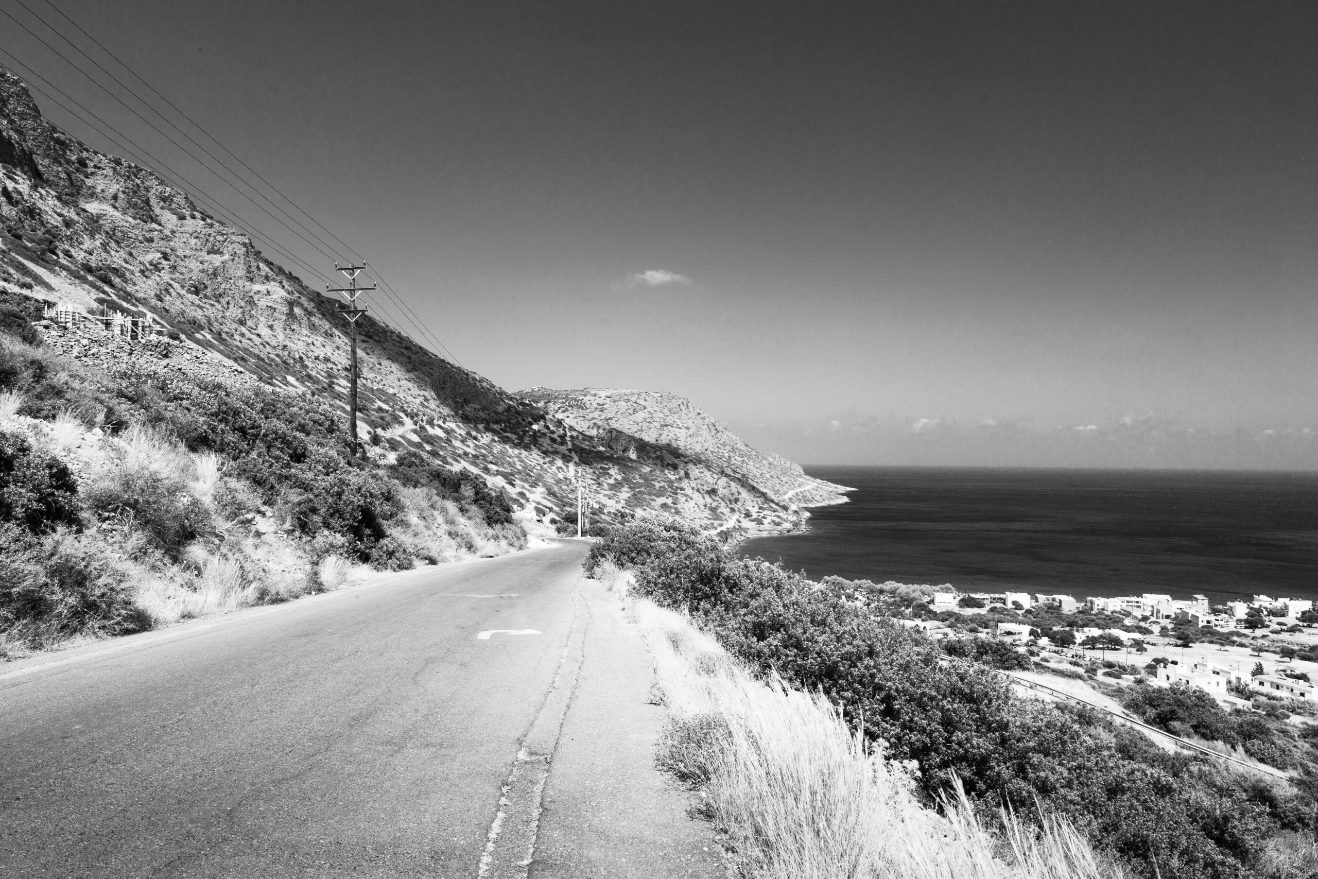 A black and white photo of a view from the top of the mountain looking down along an old road